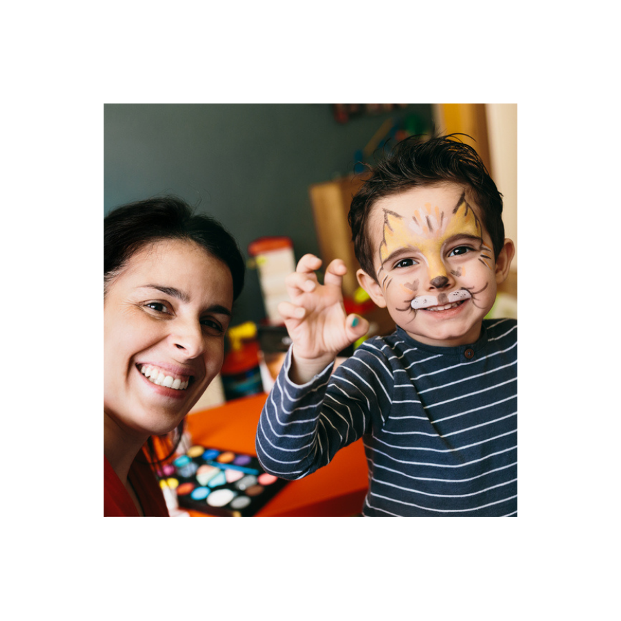 A mother and son smiling at the camera. The son has face paint like a lion.